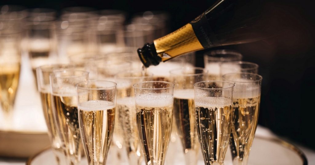 Champagne poured out from bottle to glasses
