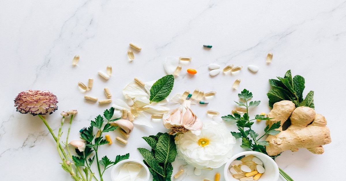 dietary supplements and flowers with flowers and herbs on a marble surface